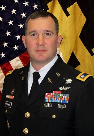 Headshot of LTC Polhamus with American flag and Notre Dame flag in background