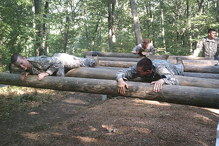 Two cadets climbing over series of logs in the Obstacle Course