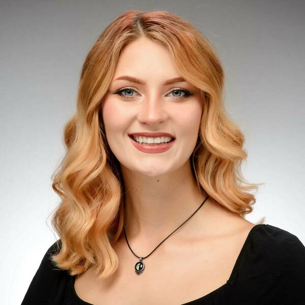 Headshot of Staff Assistant Kaylee Chapin with a grey blue background