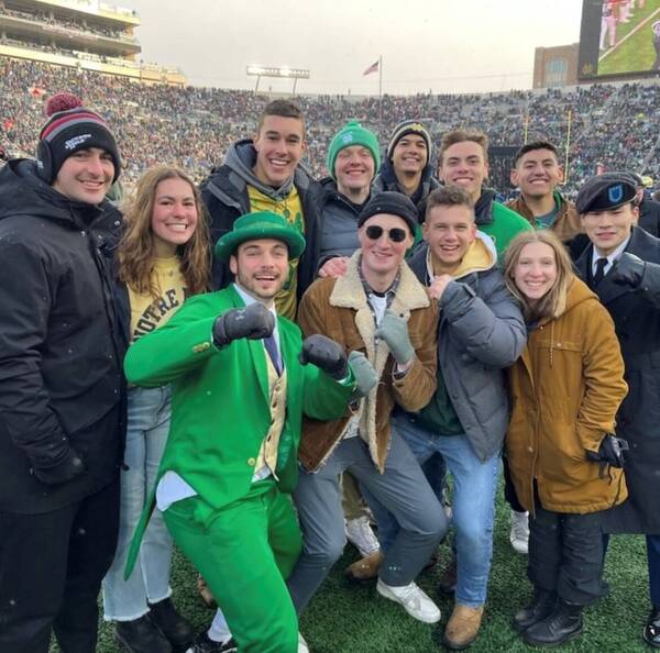 Members of the ranger challenge team pose with the Leprechaun mascot on the field at a football game